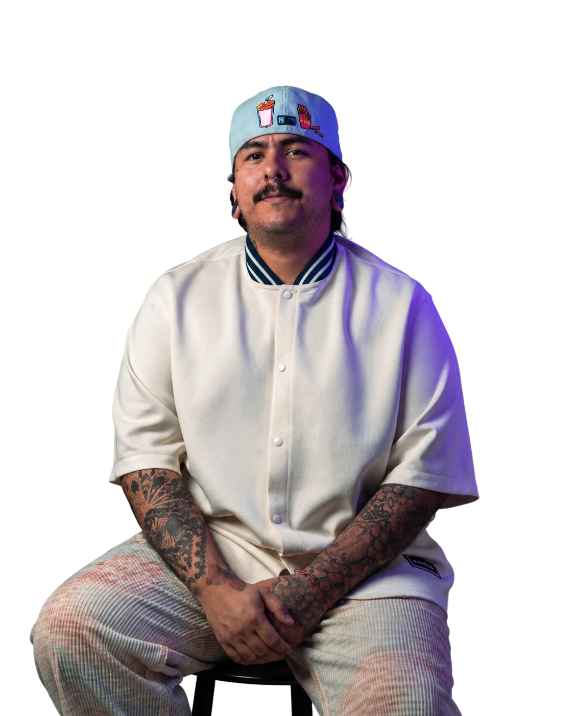Retrato de Ricardo Rivero, fundador de Odana Art, sentado con gorra celeste y los antebrazos tatuados